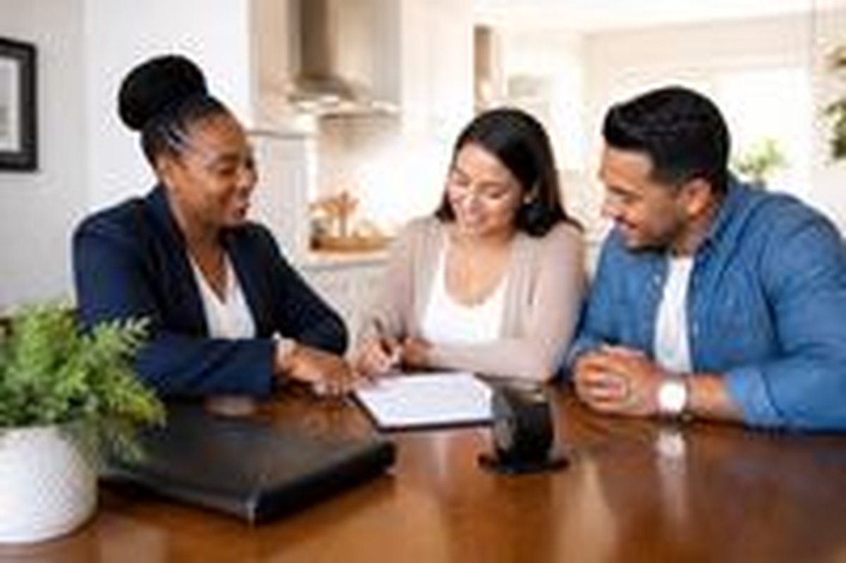 A notary helps a couple sign documents at their kitchen table