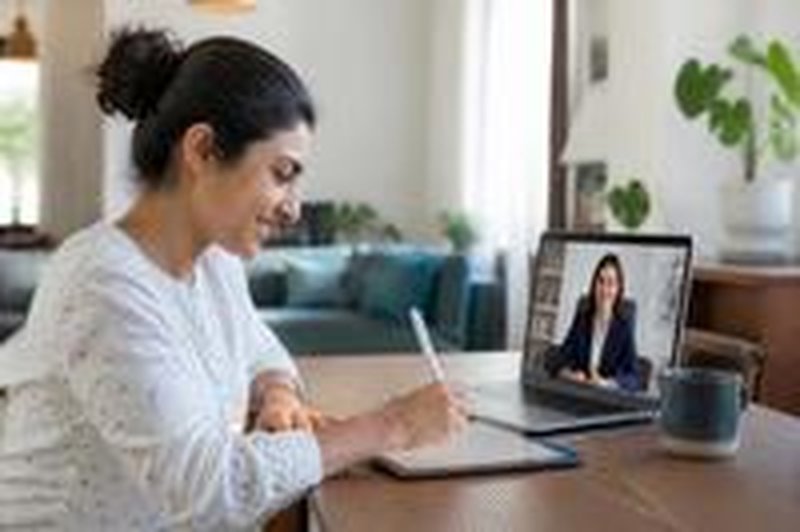 A woman signs on a tablet during a video call with a notary